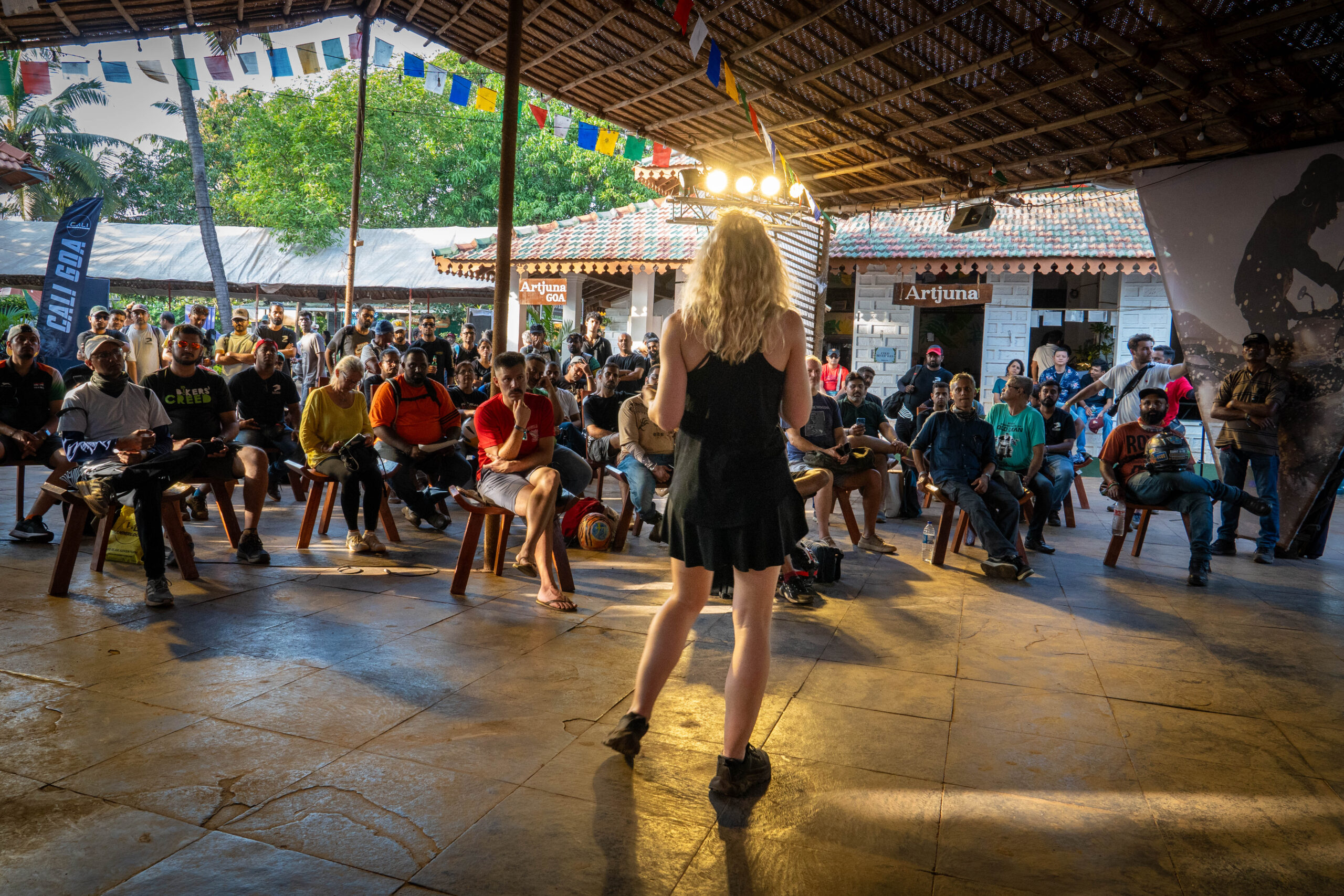 Vanessa Ruck presenting to a large outdoor audience in India at a motorcycle community event, sharing experiences from racing and adversity. At Royal Enfield MotoVerse Event, India
